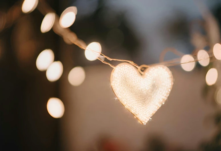 a white heart on a string with lights attached