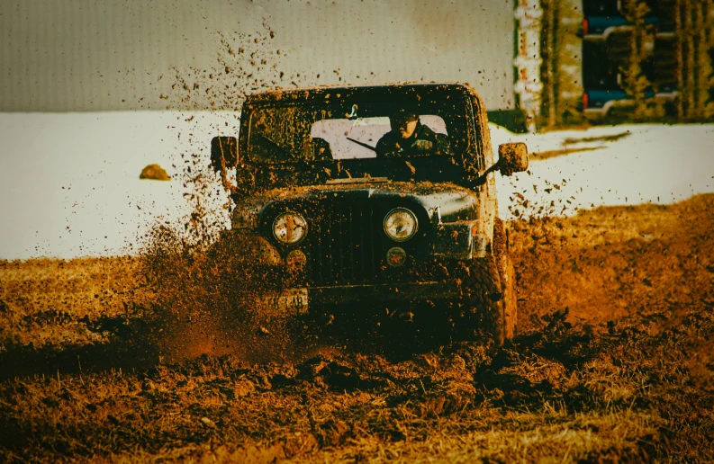 the jeep driver is driving through a field full of mud