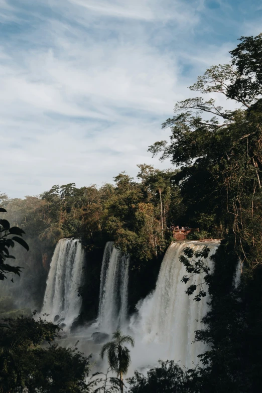 a tall waterfall with several large columns surrounded by trees