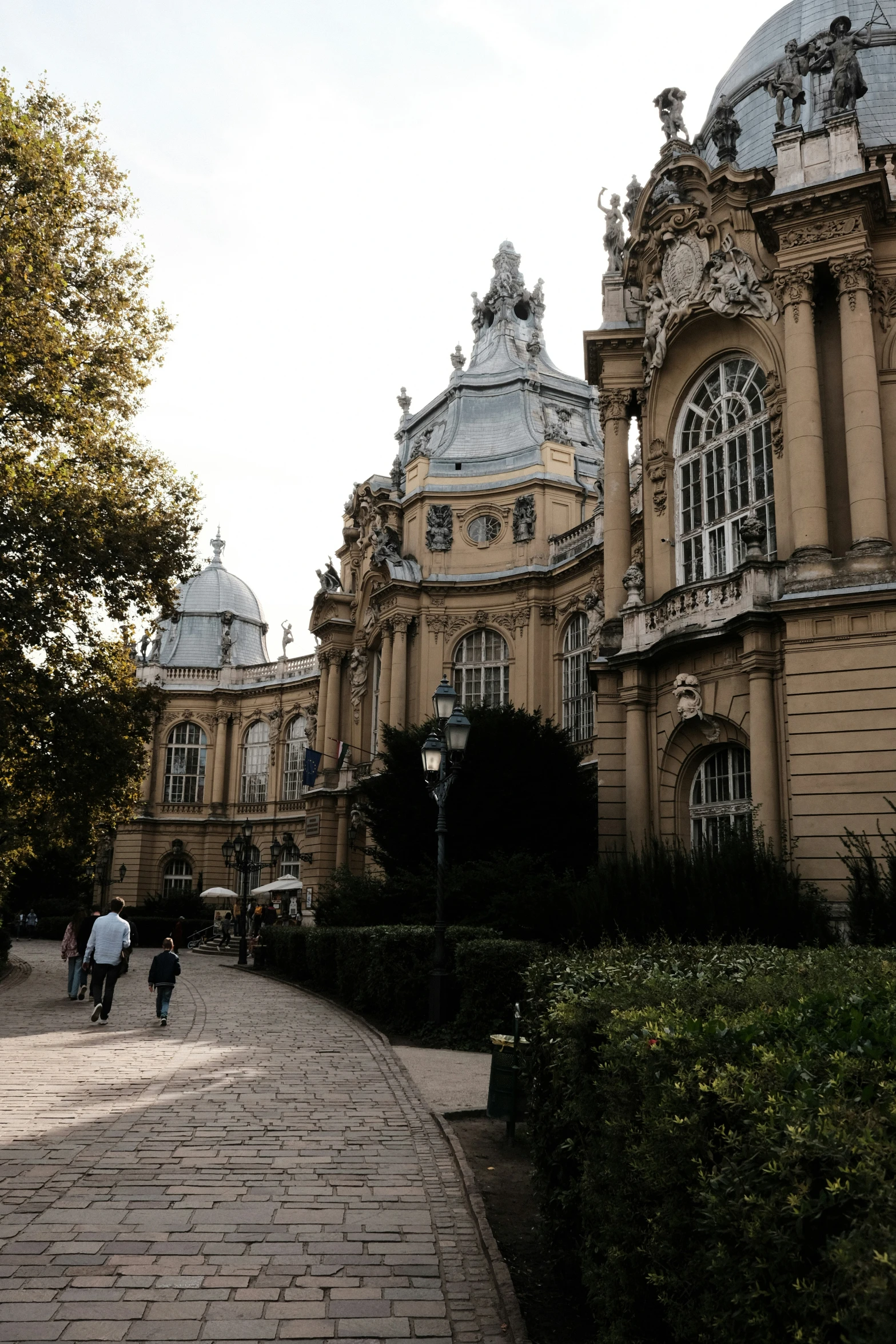 a stone pathway with two people walking in front of an ornate building