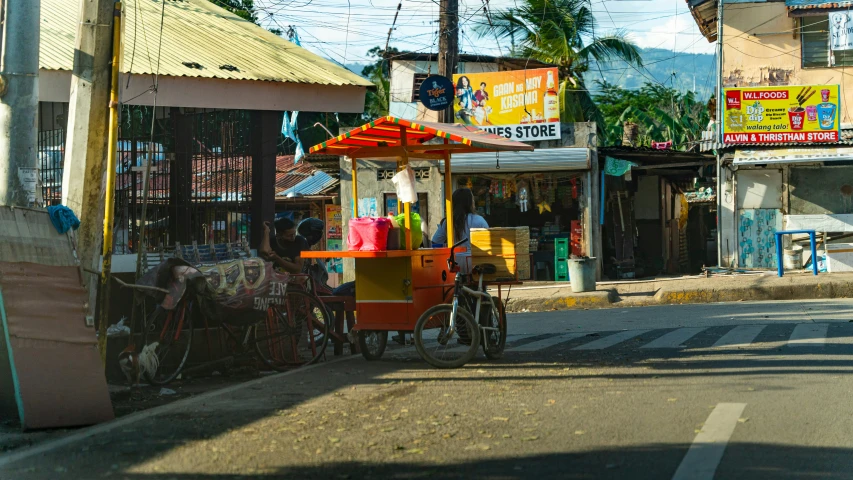 a small cart has a bicycle at the front and two people on it