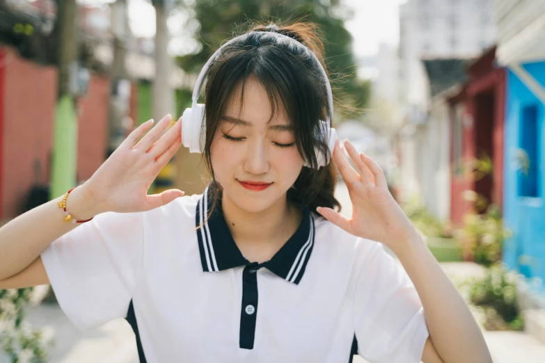 an asian girl with headphones is looking down at her hair