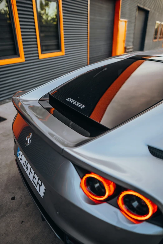 the rear of a grey sports car parked in front of a garage
