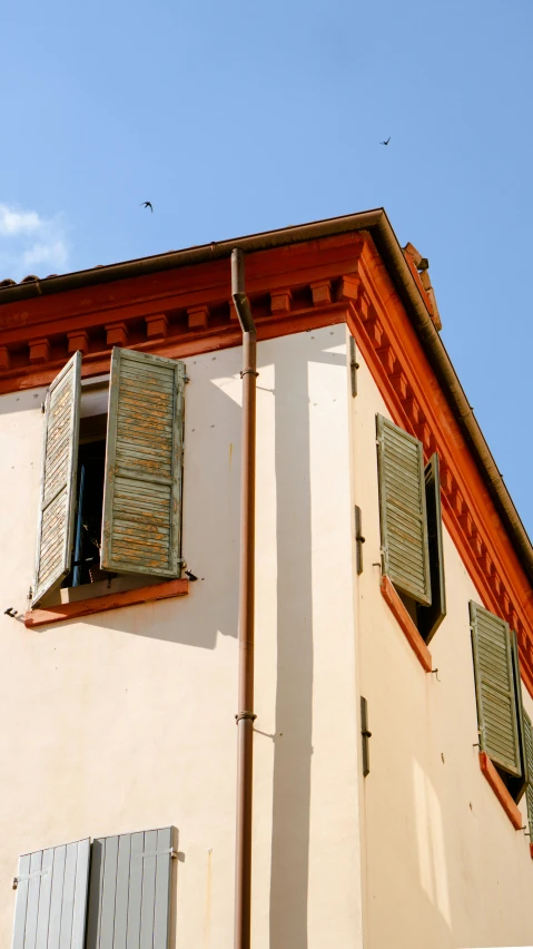 an open window on top of a building with red trim and a blue sky in the background