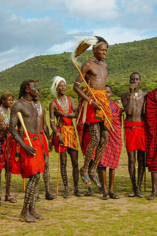 an indian tribe wearing colorful clothes with large sticks in their hands