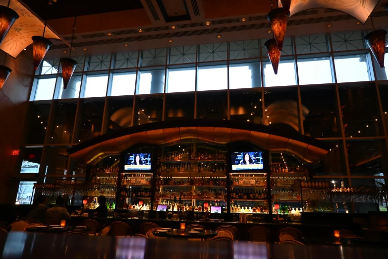 a bar with hanging lights and the television screen behind it