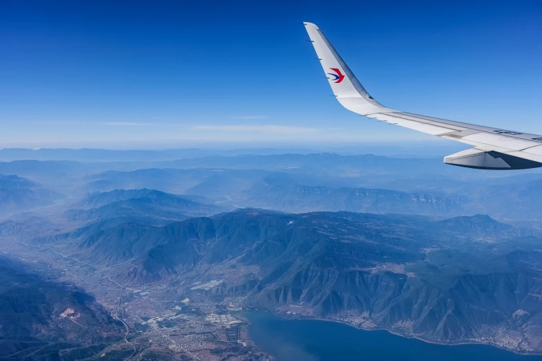 a wing of an airplane above mountains and lakes