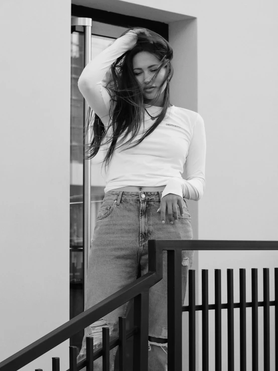 a woman in high waisted skirt, t - shirt and heels standing near balcony railing