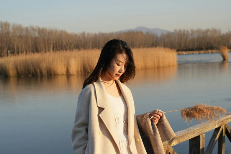 a girl is standing on a bridge near water