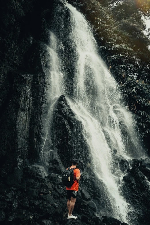 woman standing in front of a waterfall with lots of water