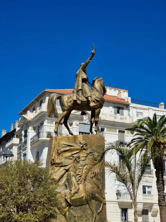 a statue of a man on a horse holding a spear near a tree