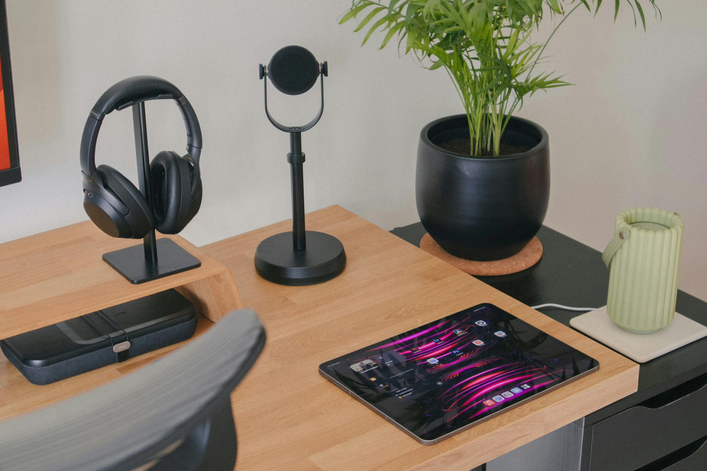 a desk has a plant and headphones, a table top phone, and a tablet