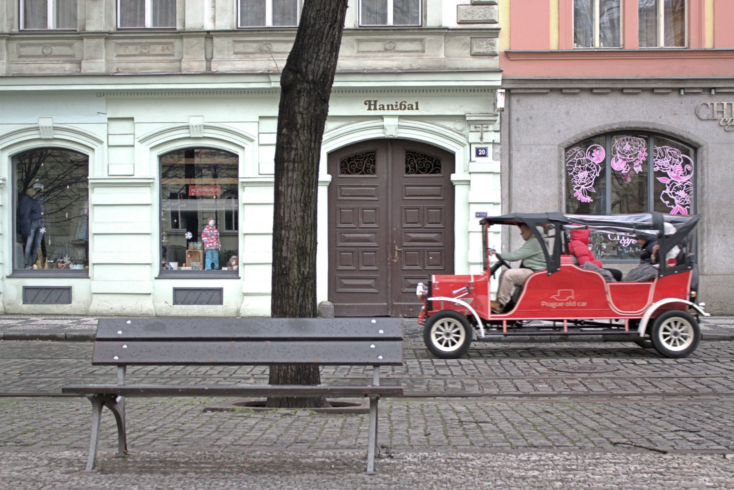 an old red car parked next to a building