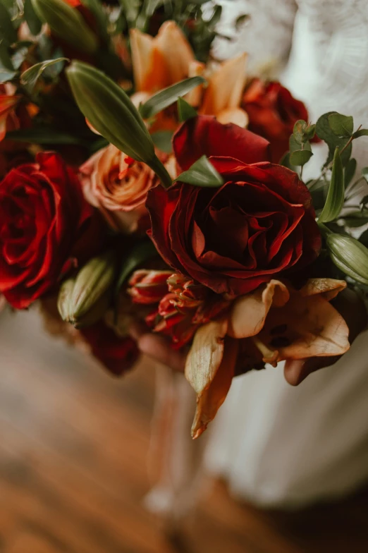 a bride holding bouquet of red and orange roses