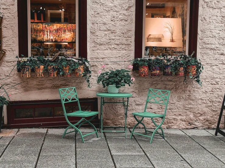 green chairs are sitting near a window, in front of a wall with pictures