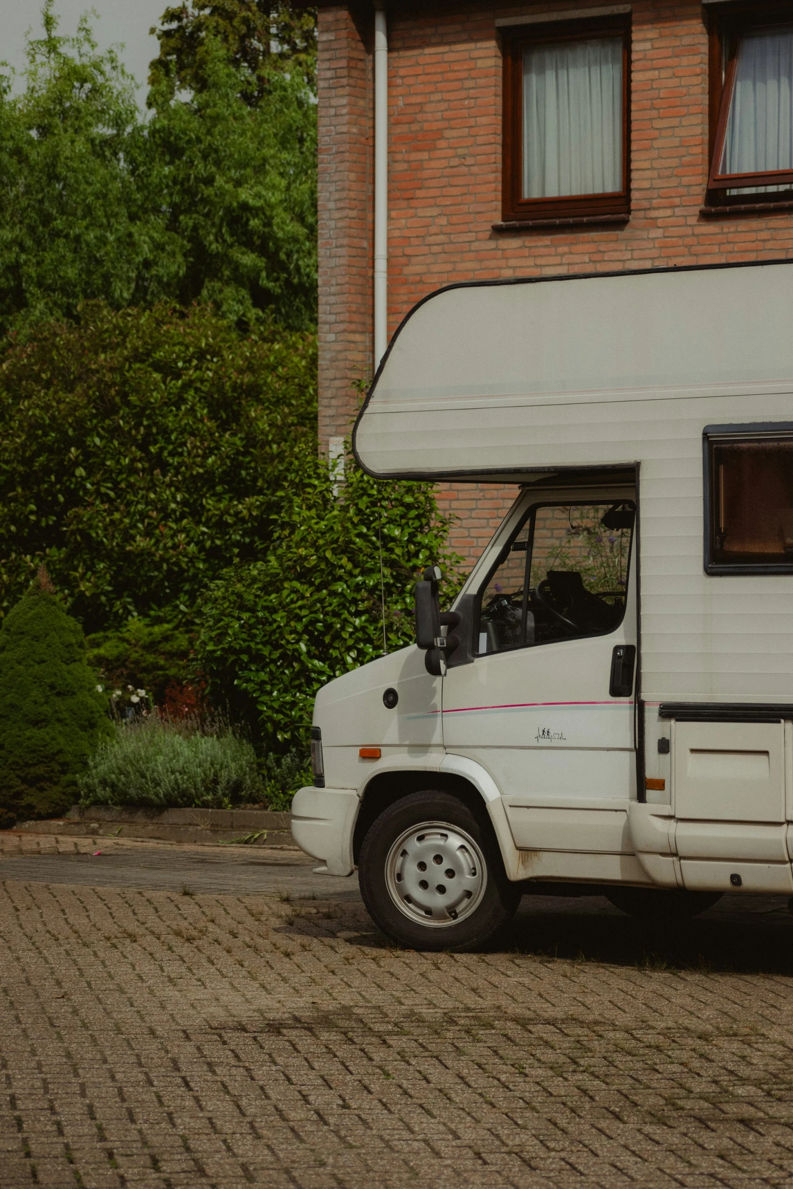 a white camper is parked on a brick driveway