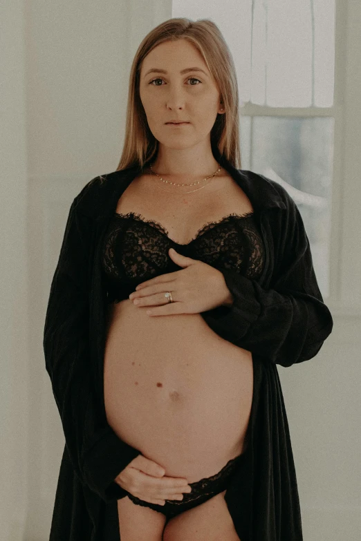 a pregnant woman is in lingerie with her hand on her hips