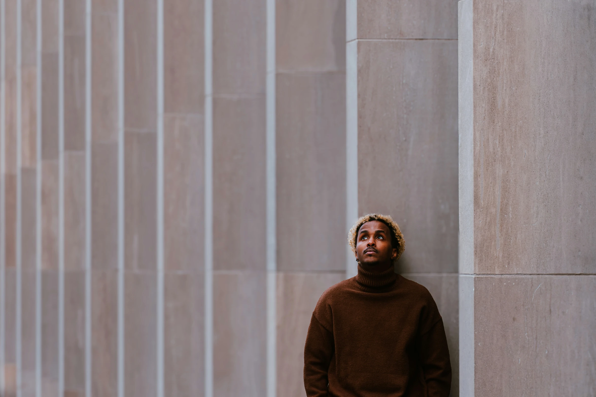 a man leans against a wall while posing