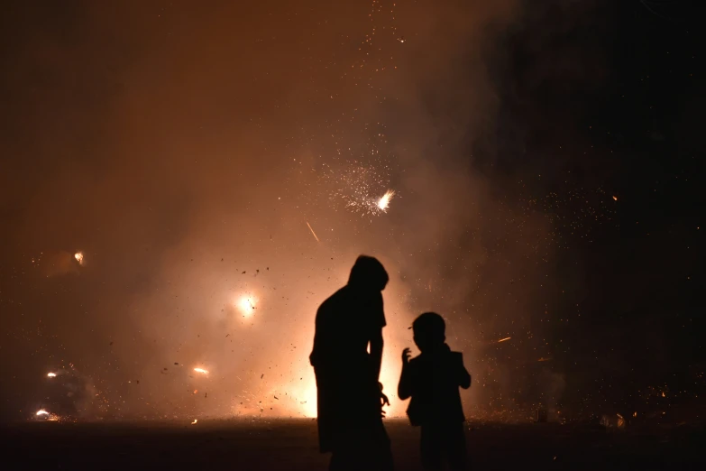 two people standing in front of a fire filled sky