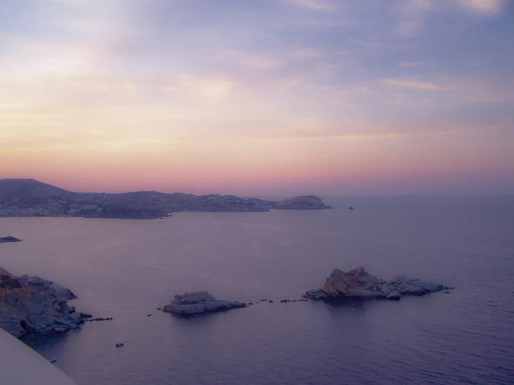 the sunset illuminates the distant blue water near some rocks