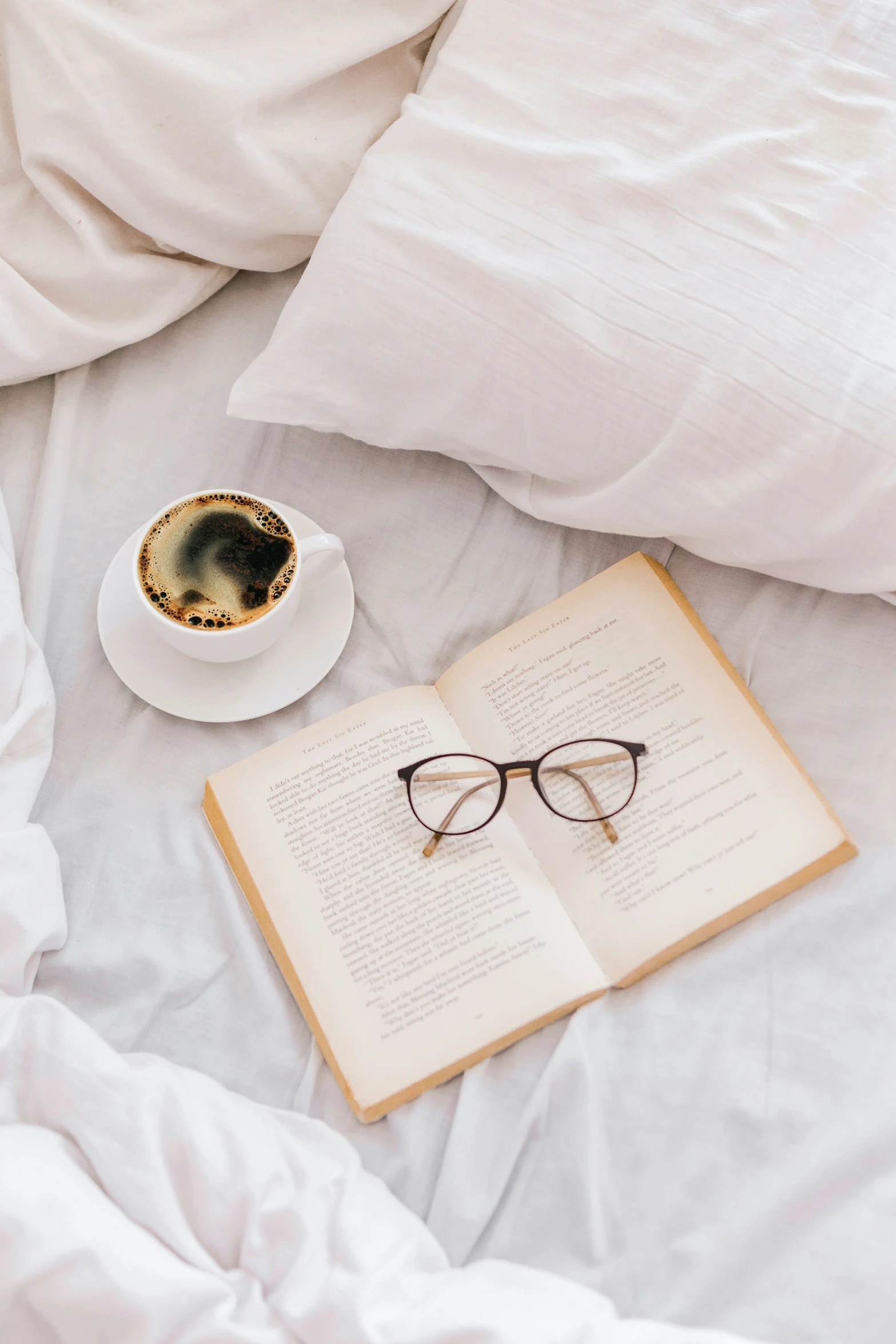 there is a cup of tea and book on the bed