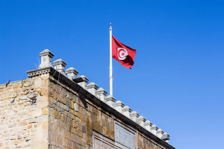 the flag is waving next to a tower that appears to have a clock on it