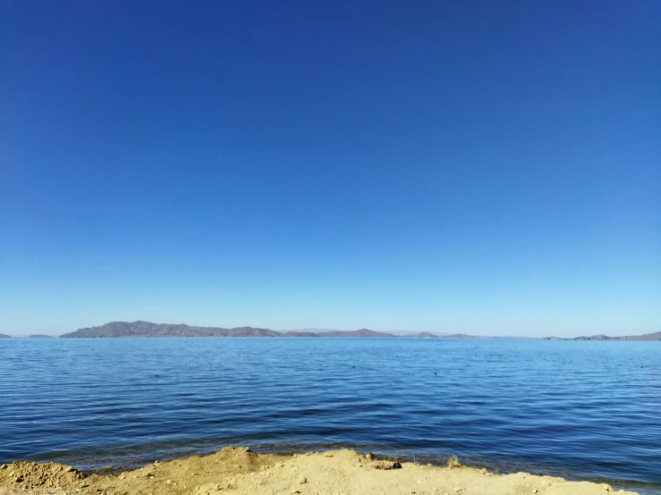 an open body of water with hills in the distance