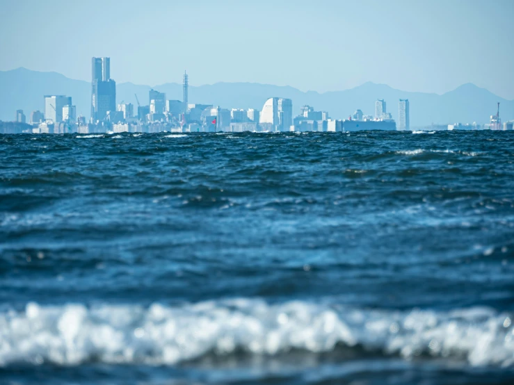 the ocean with waves and city in background