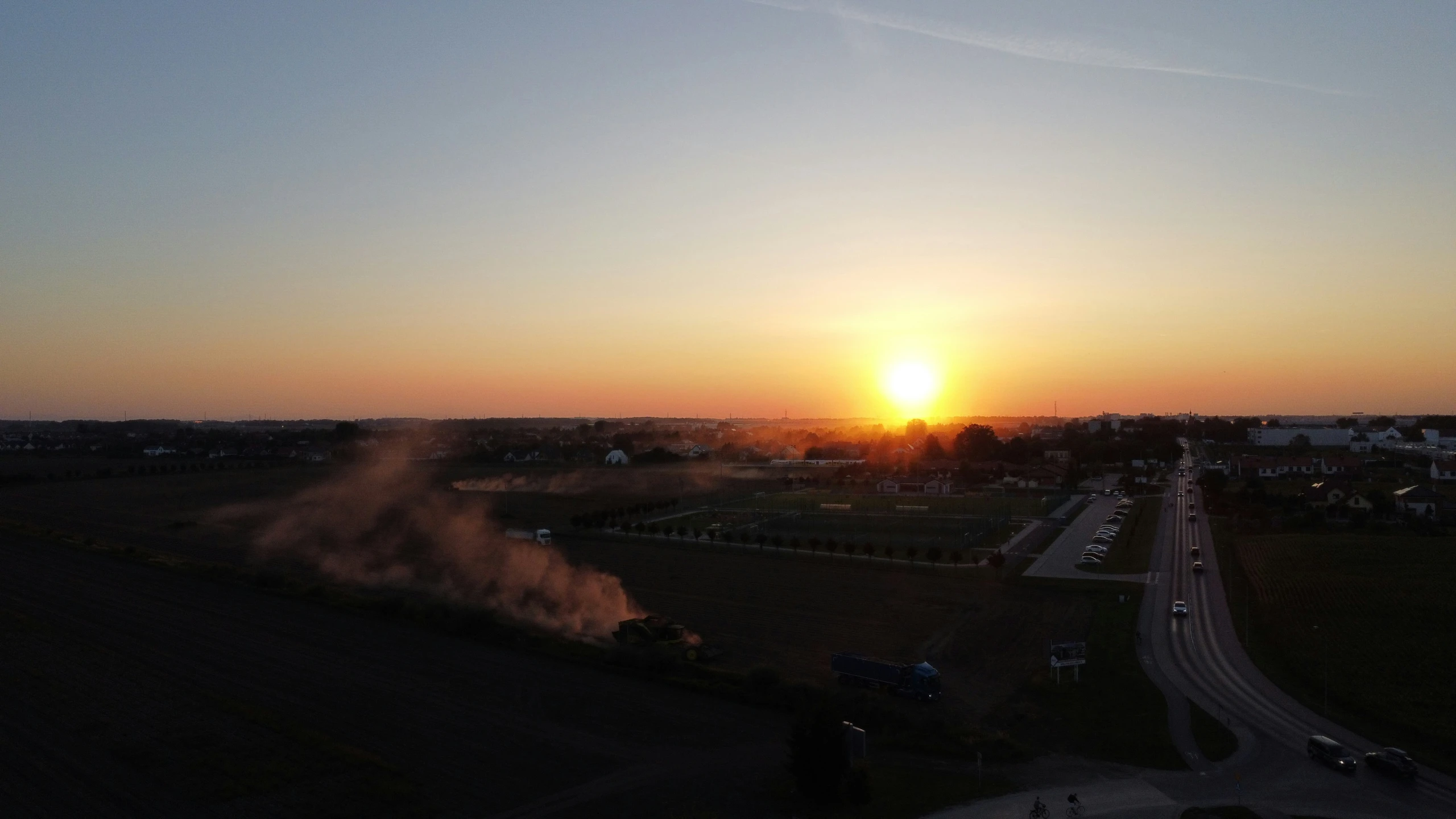 a large field at sunset with the sun in the distance