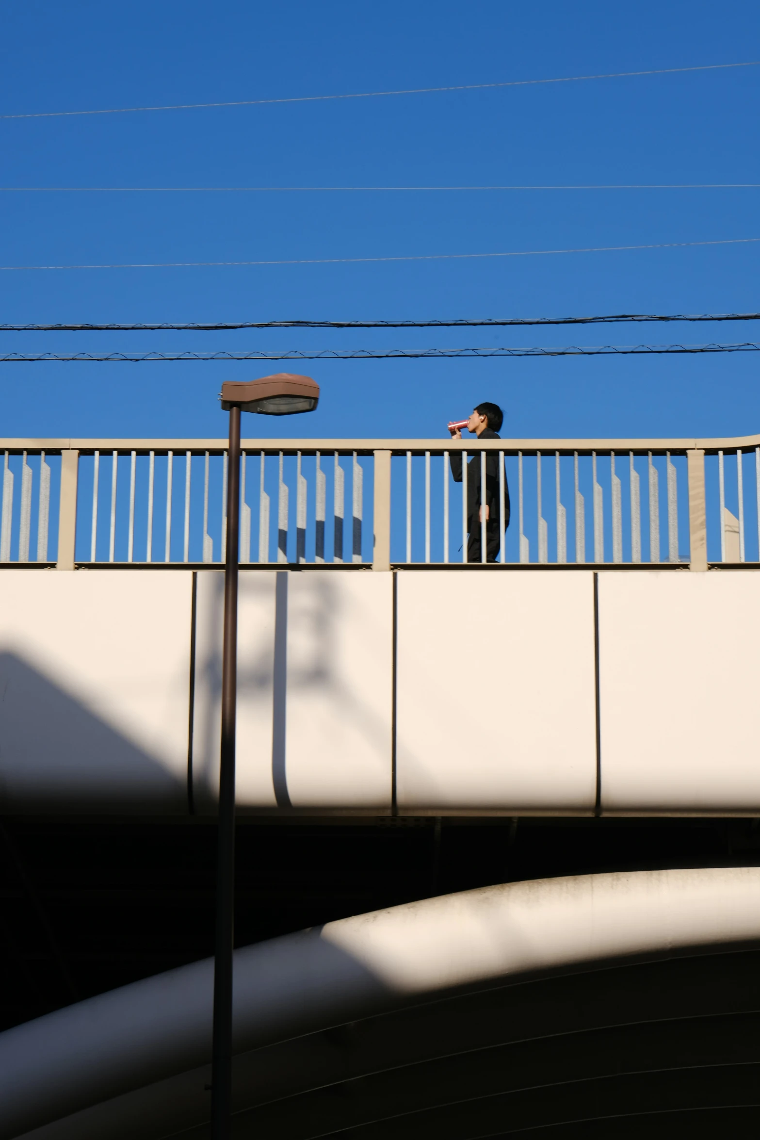 a man standing on a bridge next to traffic lights