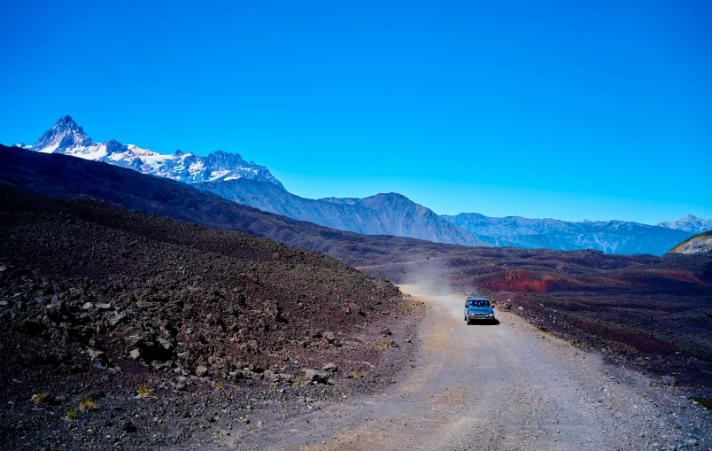 a car driving on the dirt road in the mountains