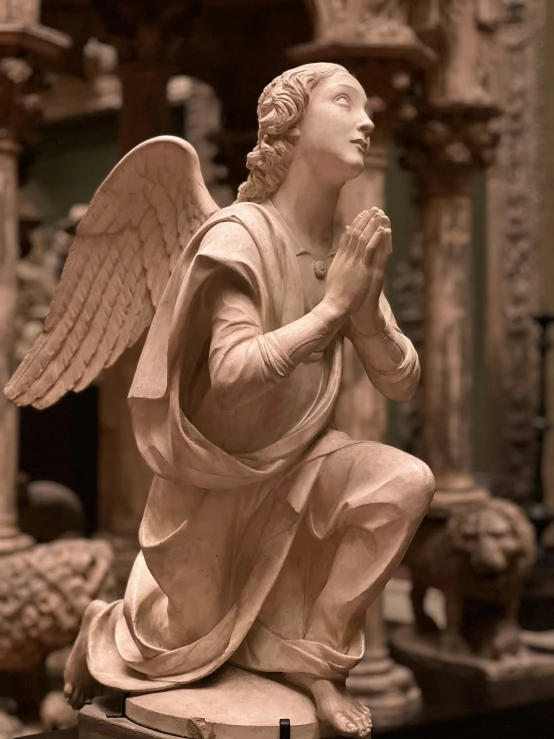 a statue of an angel praying with other statues behind