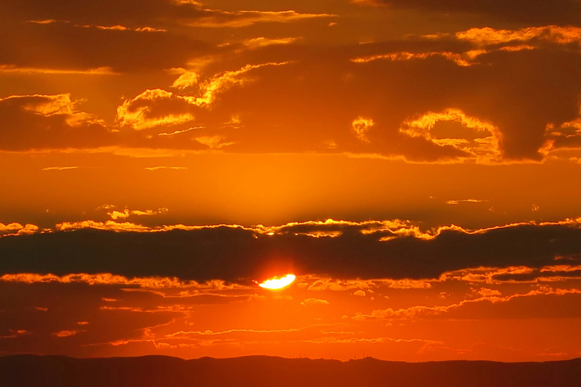 a orange sky with some clouds and some birds