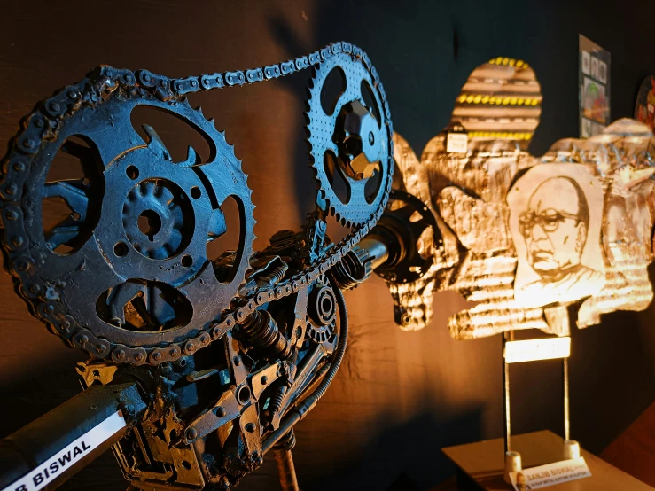 an industrial sculpture of gears in front of a building at night