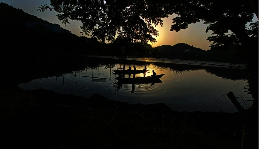 the sun sets over some water with small boats