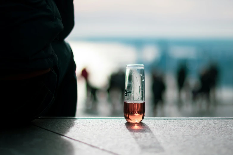 a beverage glass sitting on a ledge near a beach