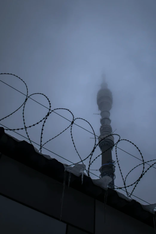 a tall tower surrounded by barbed wire in the fog