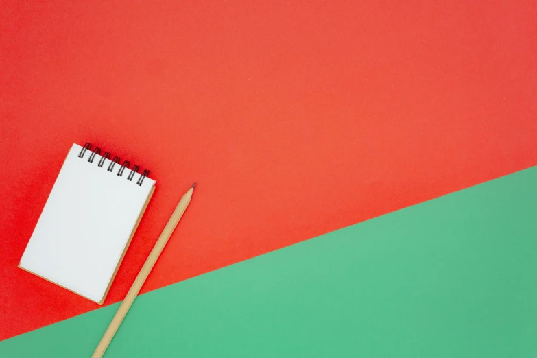 a notebook and pencil are on a red green and blue backdrop