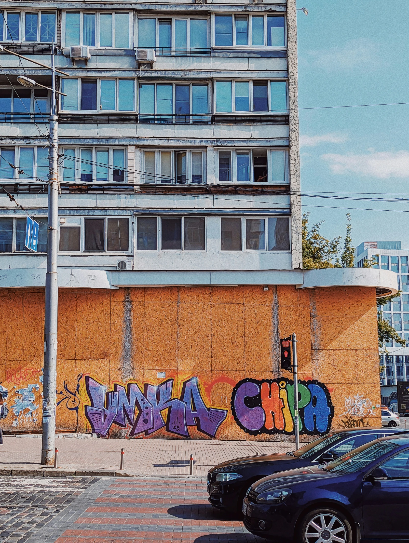 a graffiti - covered building on an orange wall in a city