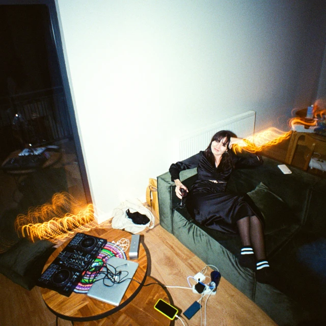 a woman sitting on a couch with electronic equipment around her