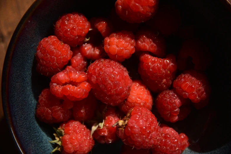 a close up of a bowl filled with raspberries