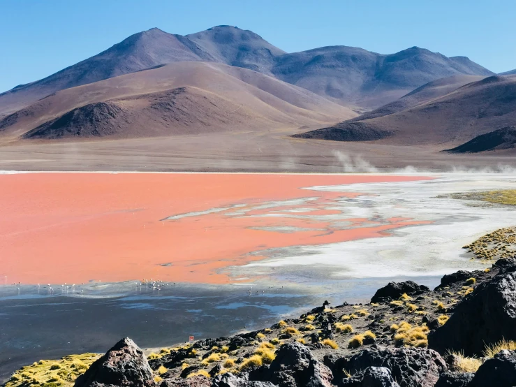 water is seen in front of some hills