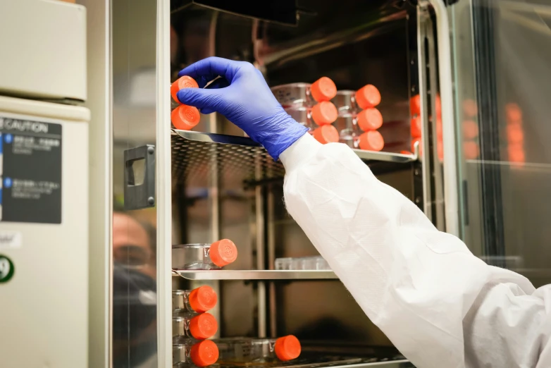 worker in white lab coat inspecting equipment inside