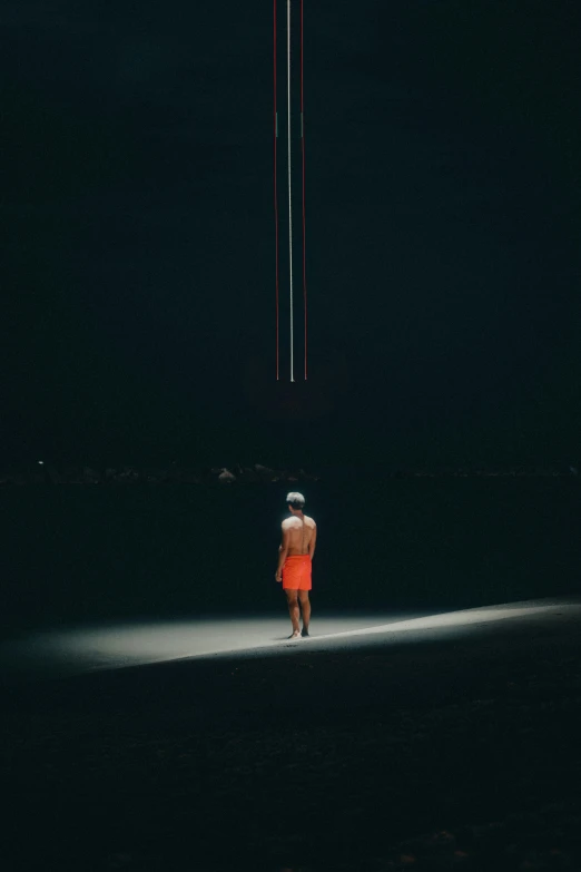 a woman standing in the dark with a kite flying overhead