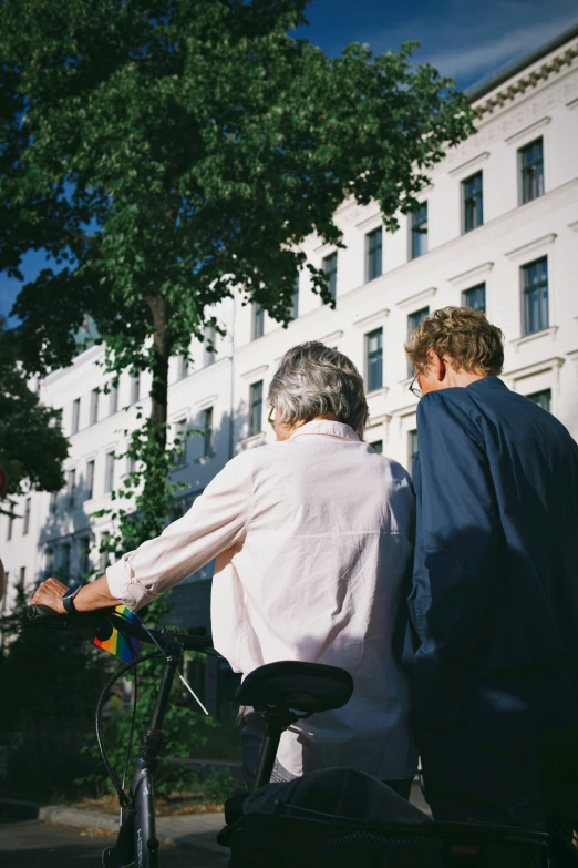 two older people riding on a bike down a street