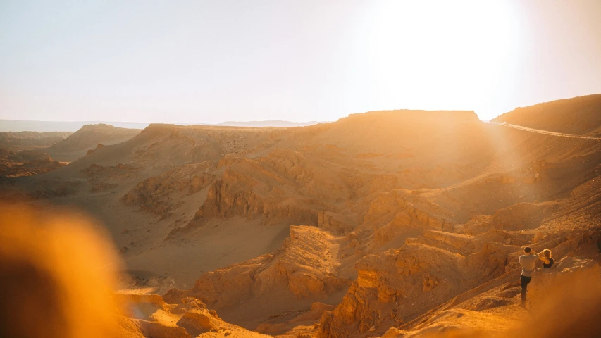 three people are walking through the desert on a hillside