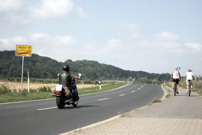 a group of people riding motorcycles down a country road