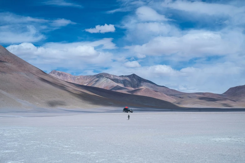 a lone hiker travels in the mountains above a vast, barren landscape