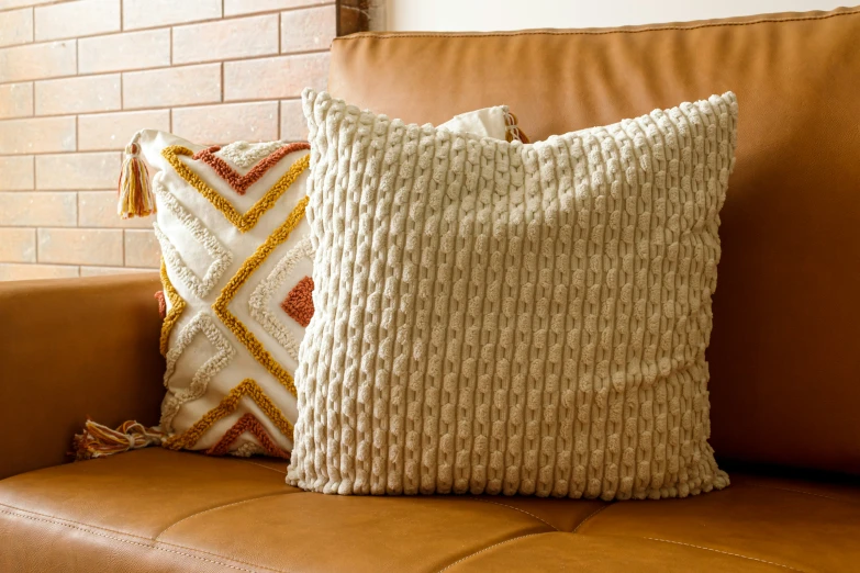 a tan couch with brown pillows and brown leather sofa