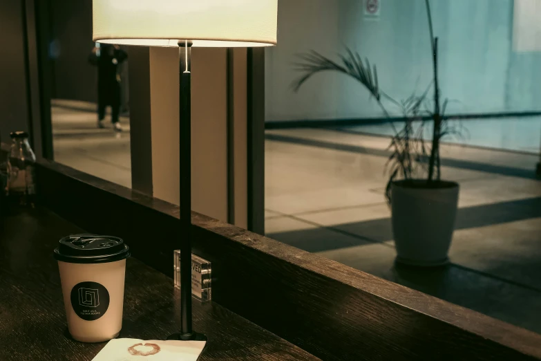 coffee cup next to a glass door and lamp